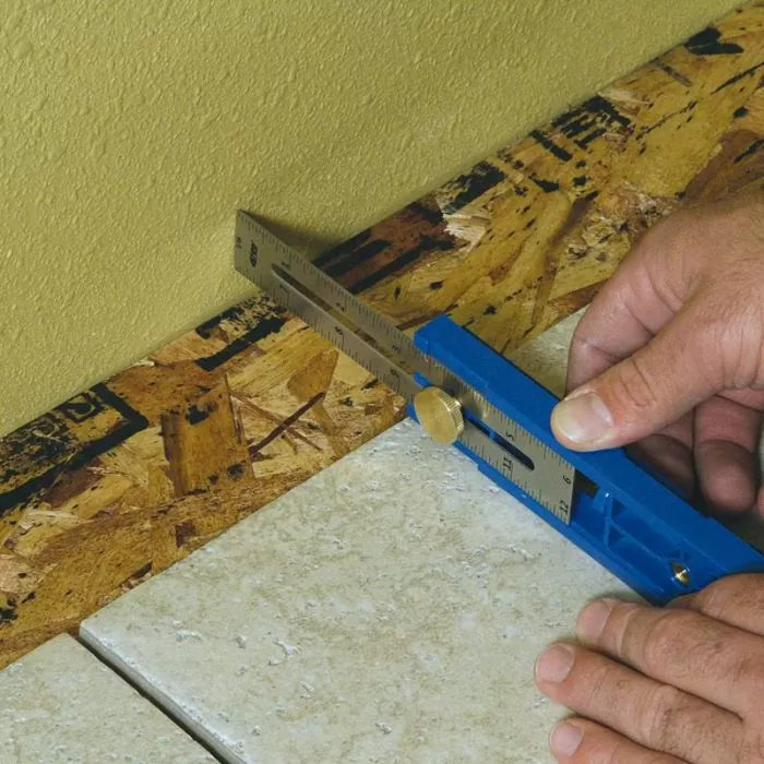 Woodworker using a marking gauge tool to measure against a wall and wood surface