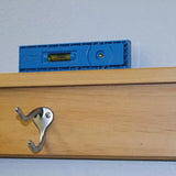 Blue plastic level on wooden shelf with silver wall hook, woodworking tool in use