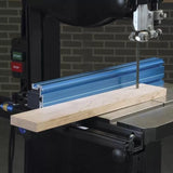 Band saw with blue aluminum fence cutting a wooden board in a woodworking shop