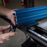 Adjusting a blue aluminum fence on a woodworking table saw with built-in measuring scale