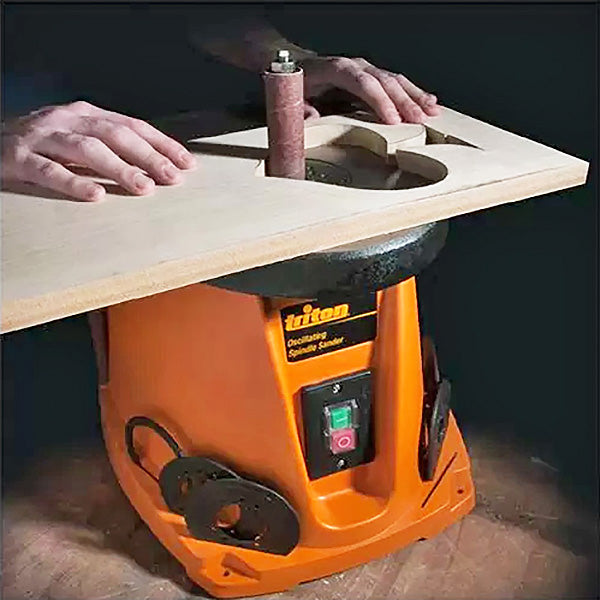 Oscillating spindle sander shaping wood panel in woodworking workshop