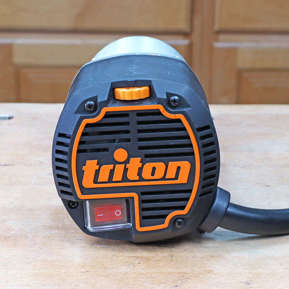 Close-up of a Triton woodworking router power tool on a workbench in a workshop setting.