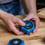 Person holding a blue non-slip woodworking bench dog on a wooden workbench