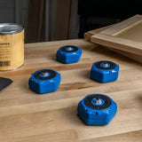 Set of four blue woodworking bench cookies on a workshop table with wood panels and finish can