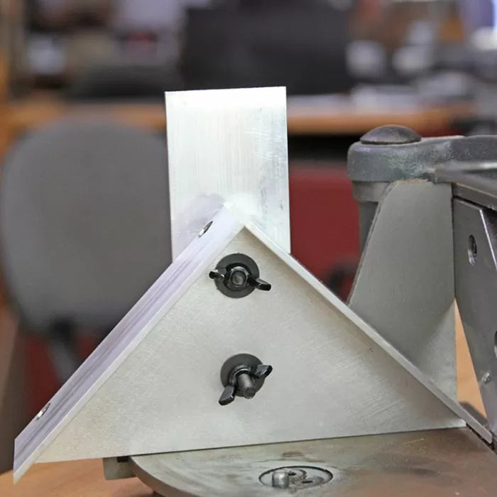 Aluminum miter gauge jig with wing nuts attached to a woodworking machine
