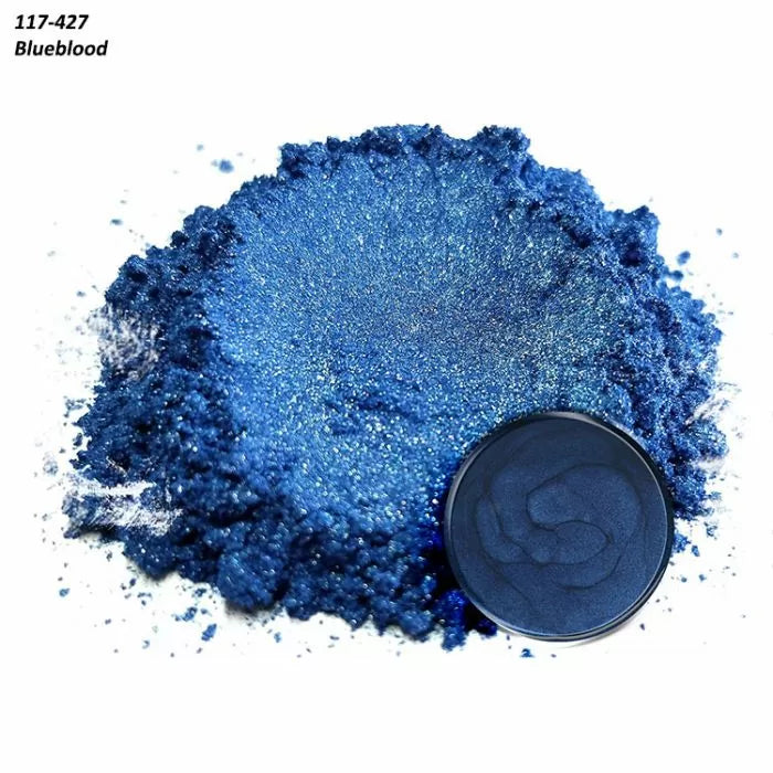Shimmering blue pigment powder with a round container of blue powder on white background.