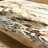 Close-up of rough, unfinished live edge wood slab with bark and natural texture