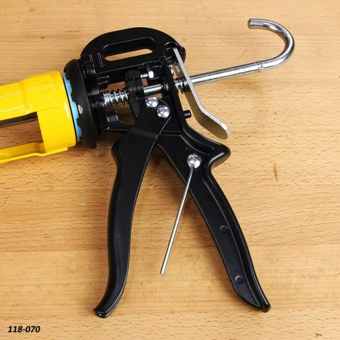 Close-up of a heavy-duty caulking gun on a wood workbench, carpentry hand tool