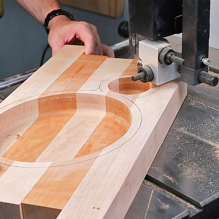 Woodworker using bandsaw to cut circular shapes in striped hardwood board