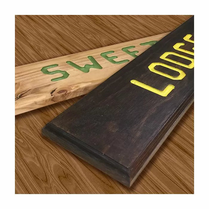 Wooden signs with carved, painted letters on a wood surface, showcasing woodworking router skills.