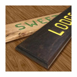 Wooden signs with carved, painted letters on a wood surface, showcasing woodworking router skills.