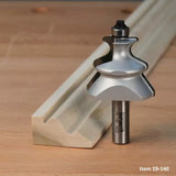 Woodworking router bit with decorative profile alongside moulded wood trim on workbench