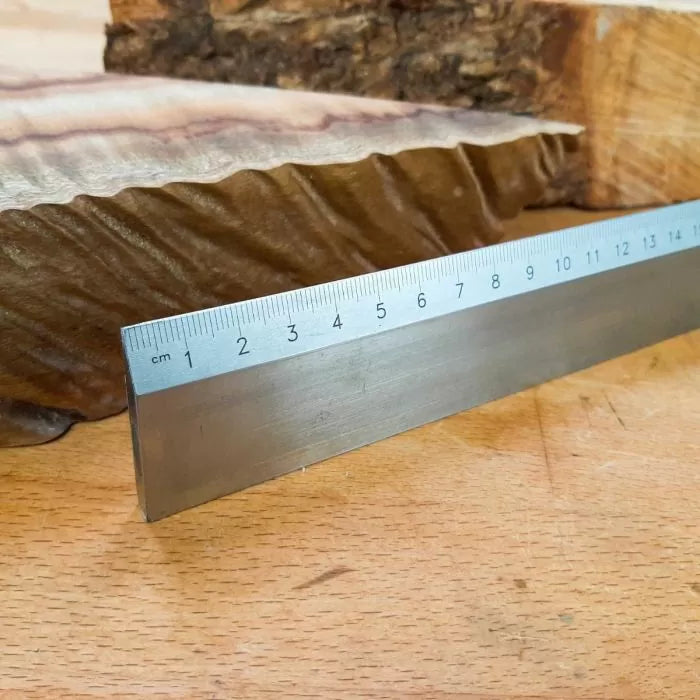 Close-up of a ruler measuring a wavy live edge wood slab on a workbench, woodworking tools