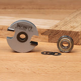 Slot cutter router bit, bearing, and shims on a woodworking table near a grooved wood piece.