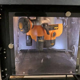 Woodworking router mounted inside a dust enclosure for precision cutting