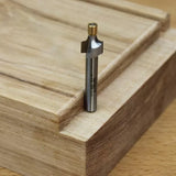 Carbide router bit on stacked wood showing precise joinery groove