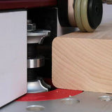 Router bit shaping edge of square wood block on a woodworking router table