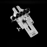 Adjustable metal woodworking drill guide jig with measurement markings and bracket on black background