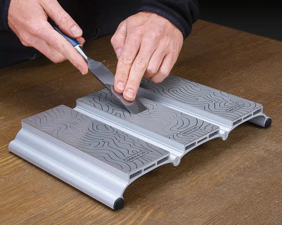 Sharpening a chisel on a 600 grit diamond sharpening stone with textured surface on wood table