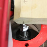Close-up of a woodworking router bit shaping the edge of a wood board on a router table
