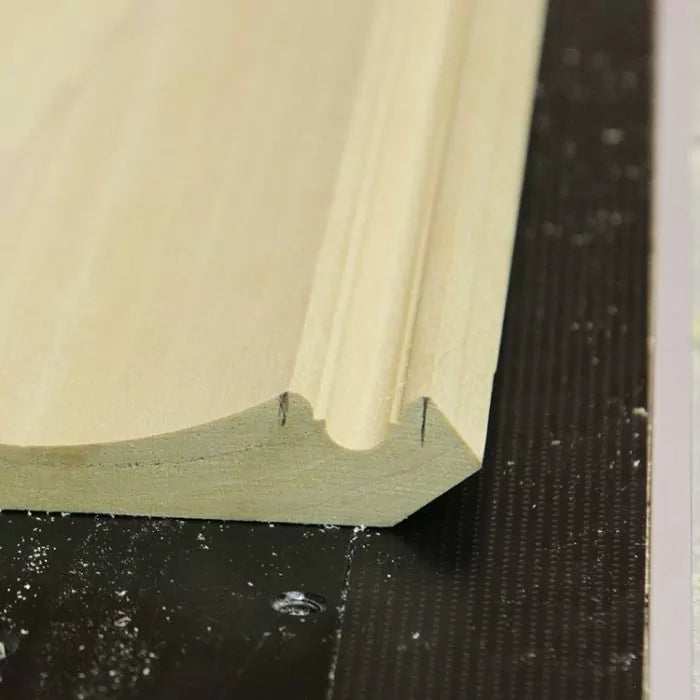 Close-up of decorative wooden molding with a detailed routed profile on a workshop table.