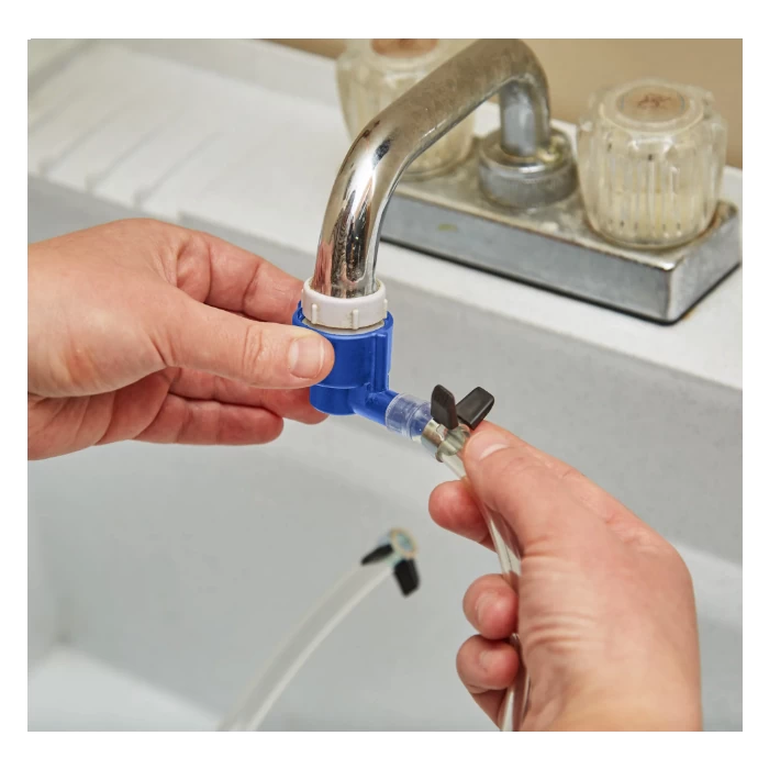 Hands attaching hose adapter and shutoff valve to metal faucet above white sink