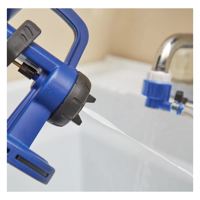 Blue handheld pressure sprayer nozzle with adjustable tip spraying water near a utility sink