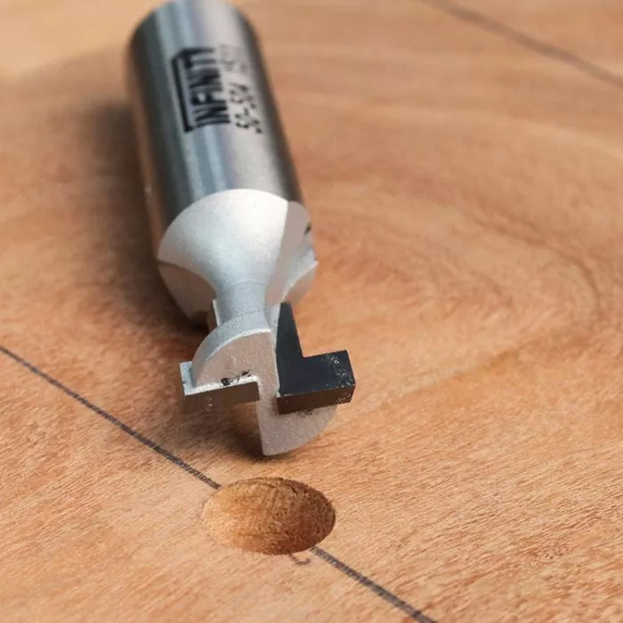 Keyhole router bit on wood surface with drilled hole, used for woodworking precision cuts