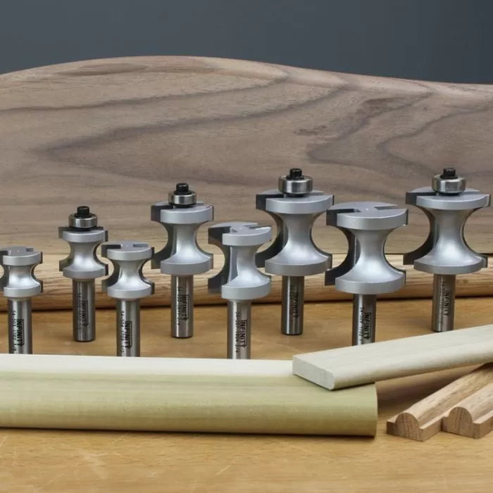Set of woodworking router bits for shaping and edging wood, displayed on a workbench.