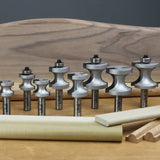 Set of woodworking router bits for shaping and edging wood, displayed on a workbench.
