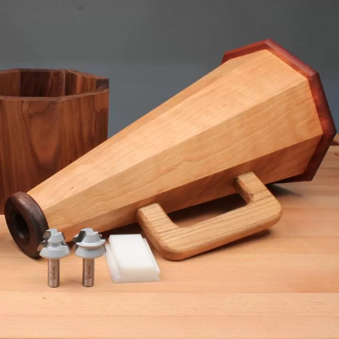 Woodworking project kit with wooden megaphone, two router bits, and jig accessories on workbench.