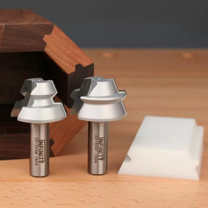 Two woodworking router bits with steel shanks and silver cutting edges on a wooden surface.