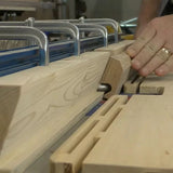 Woodworker using a router table to mill precise slots in hardwood board