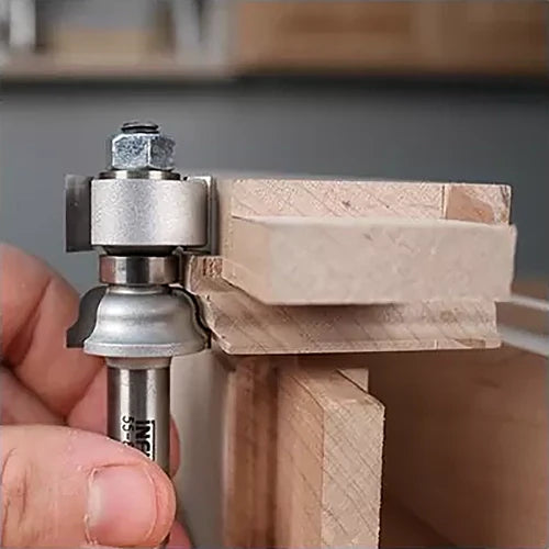 Hand holding a rabbeting router bit against wooden boards for precise joinery work