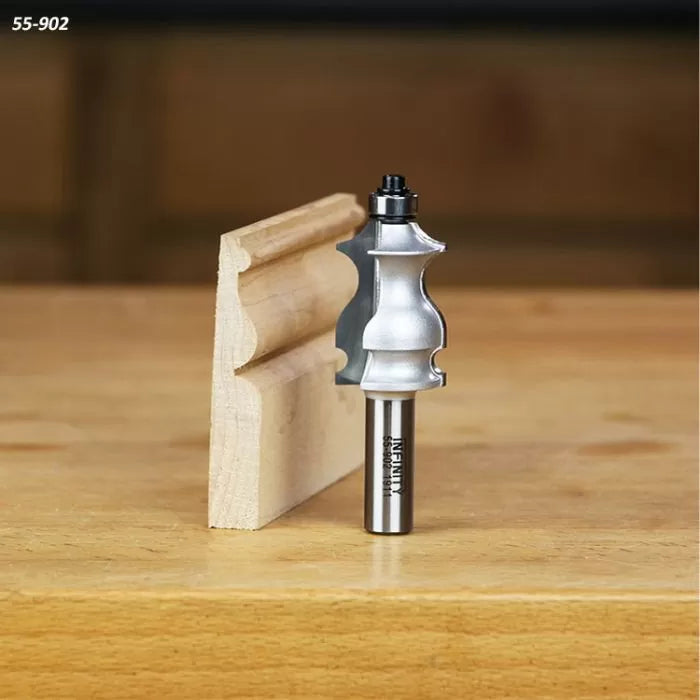 Roman ogee router bit with ball bearing beside decorative crown molding wood sample