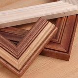 Assorted wooden picture frame moldings with detailed profiles on a wood surface.
