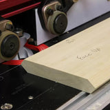 Woodworking router table with bit shaping a wooden board marked 'Face Up' and 'Wall'.