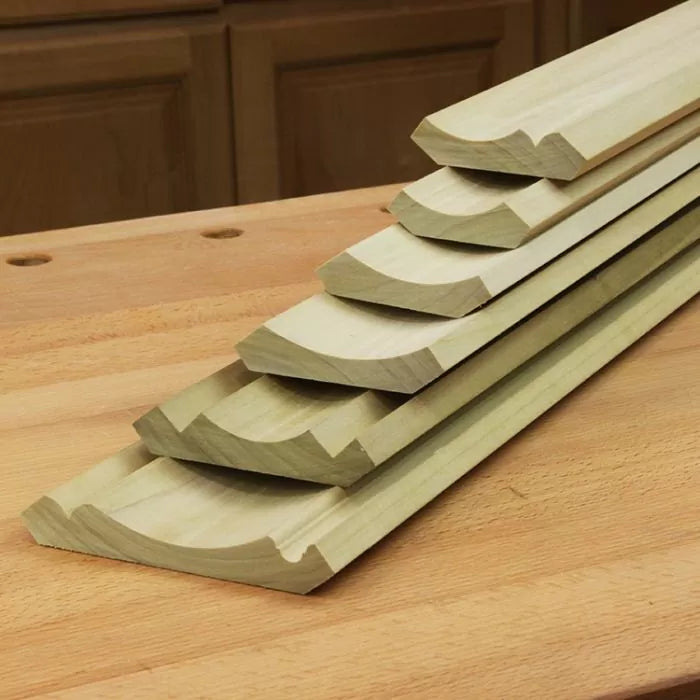 Stacked cove molding wood trim pieces on a woodworking bench