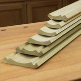 Stacked cove molding wood trim pieces on a woodworking bench