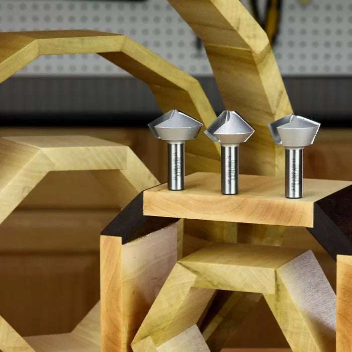 Three chamfer router bits for woodworking displayed on a geometric wooden stand