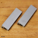 Pair of metal jointer knife sharpening jigs on a wooden surface