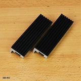Pair of black aluminum woodworking vise jaw covers with grooves on wood surface