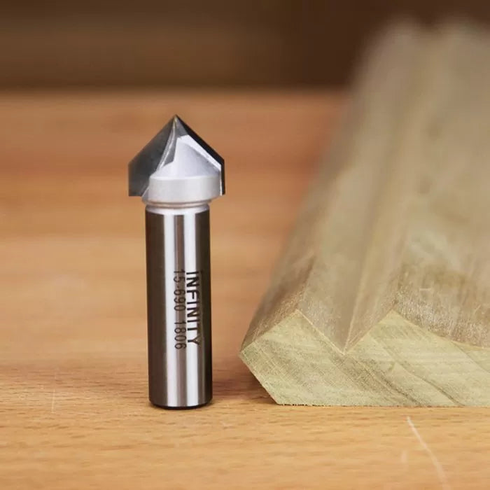 Carbide router bit with sharp angled tip on wood surface beside a beveled wooden board