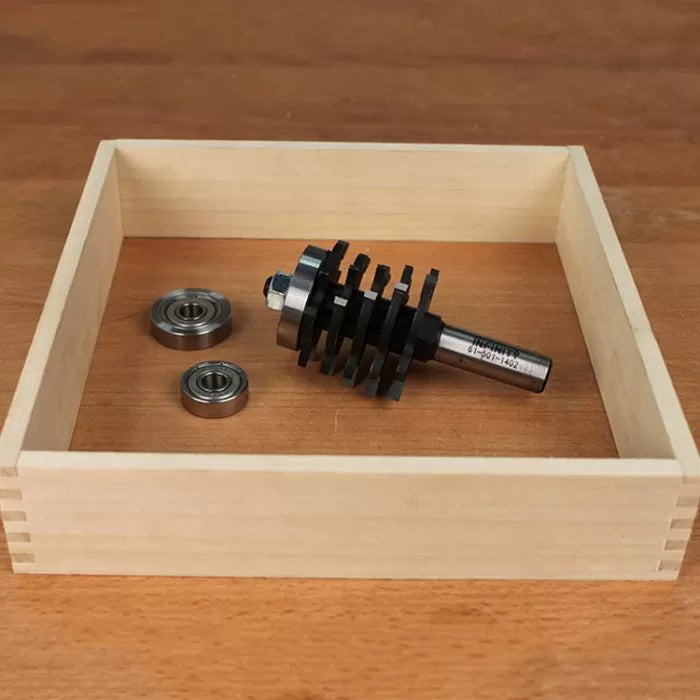 Dado router bit set and two bearings inside a wooden box on a workbench