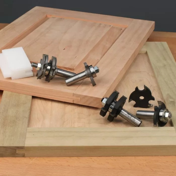 Cabinet door rail and stile router bit set on wooden panels, woodworking tools display