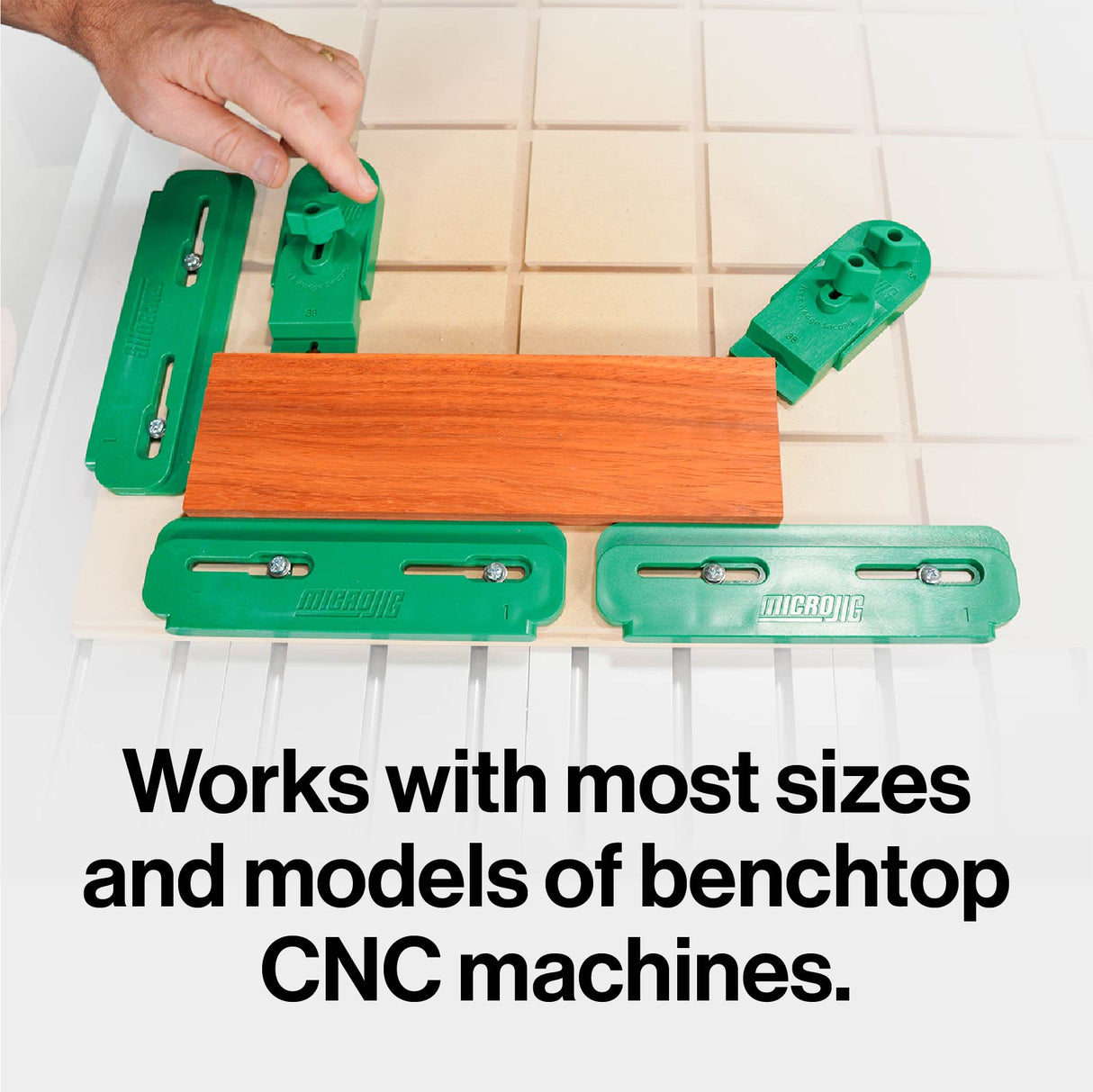 CNC clamping kit with green hold-down clamps securing wood on a benchtop CNC machine.
