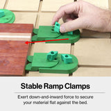 Hand adjusting green CNC ramp clamps securing wooden board on MDF worktable, woodworking tool setup.
