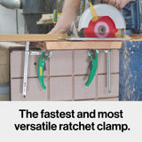 Circular saw cutting wood secured by green ratchet clamps on a workbench, woodworking tools.