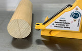 Wood dowel rod next to yellow woodworking jig with adapter connector on workbench