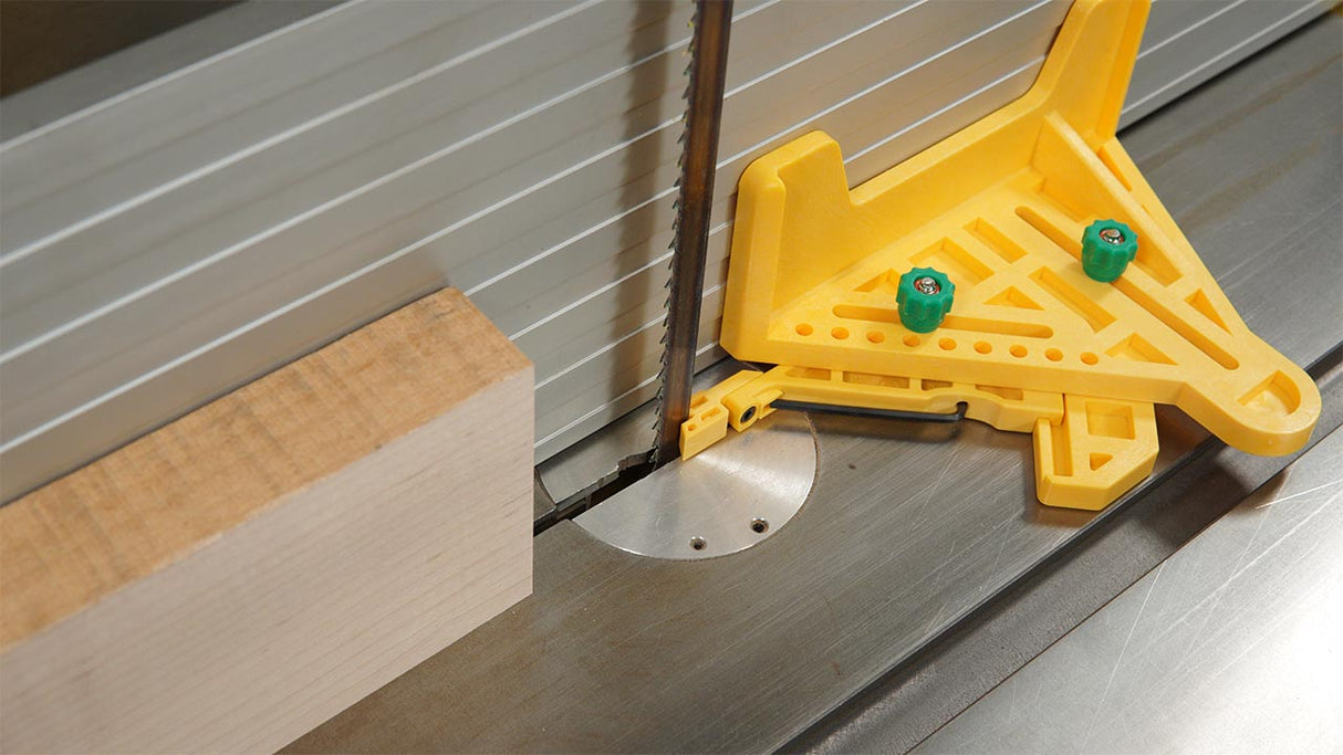 Wood being cut on a band saw with a yellow safety fence and metal guide
